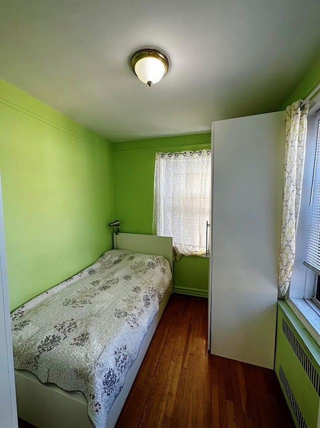 bedroom with radiator, dark hardwood / wood-style flooring, and multiple windows