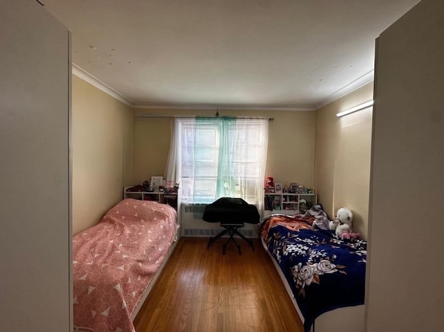 bedroom featuring wood-type flooring, radiator heating unit, and ornamental molding