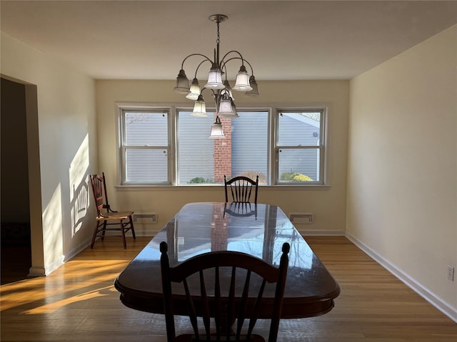 dining space featuring dark wood-type flooring and an inviting chandelier