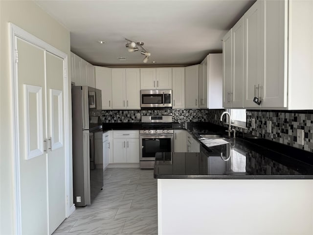 kitchen with white cabinetry, stainless steel appliances, kitchen peninsula, and sink