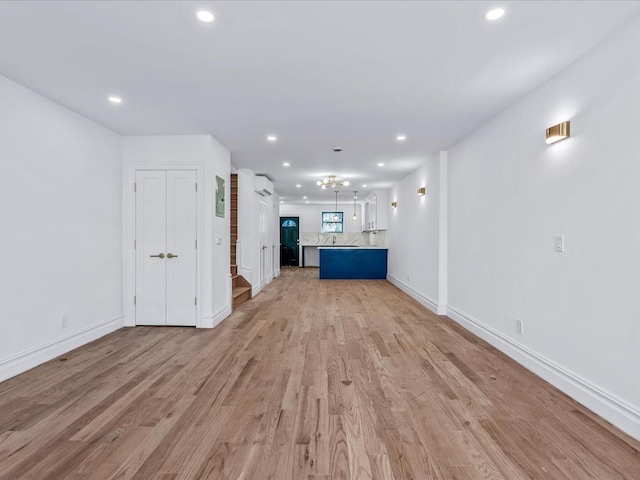 unfurnished living room featuring a wall mounted air conditioner and light hardwood / wood-style floors