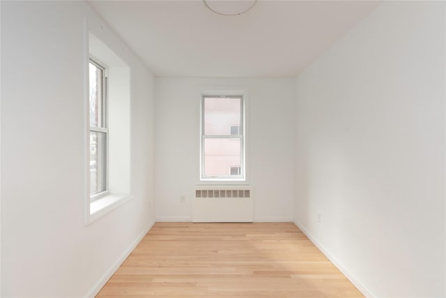 spare room featuring radiator and light wood-type flooring