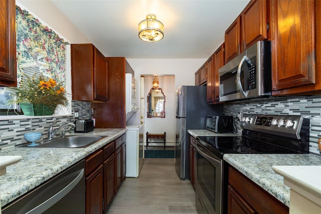 kitchen featuring sink, light stone countertops, appliances with stainless steel finishes, and decorative backsplash