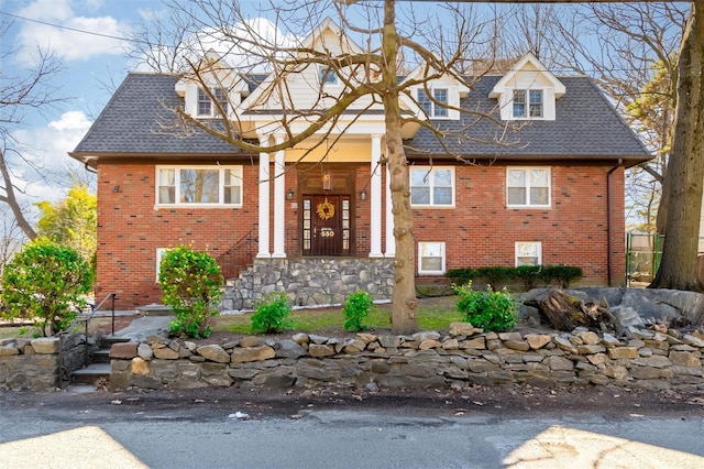 view of front of house with brick siding and roof with shingles