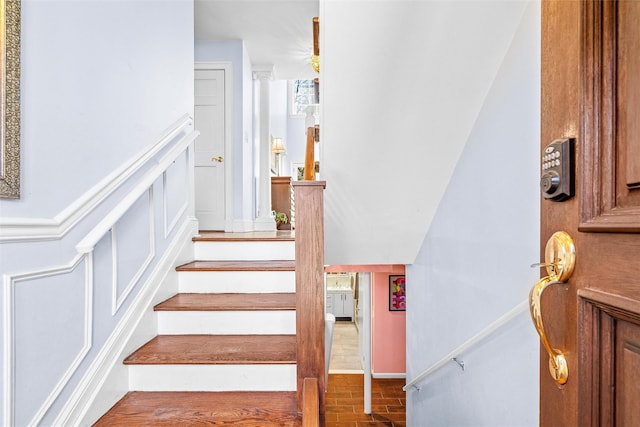 stairs featuring a decorative wall and brick floor