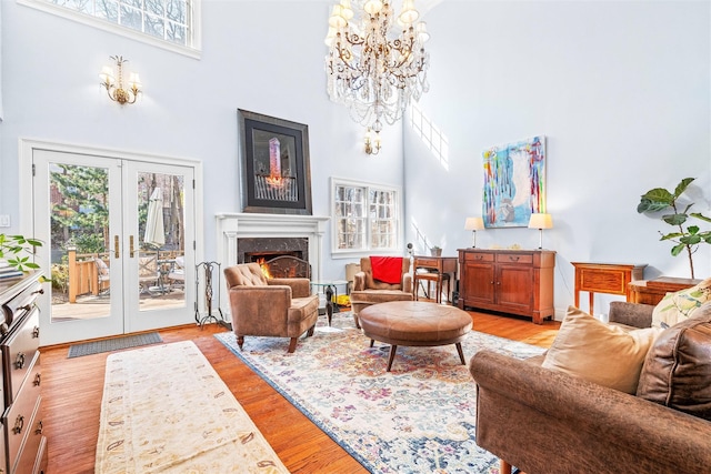 living room with light wood-style flooring, french doors, a high ceiling, and a premium fireplace