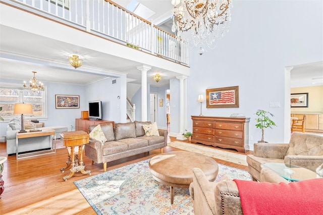 living area featuring a high ceiling, decorative columns, wood finished floors, and a chandelier