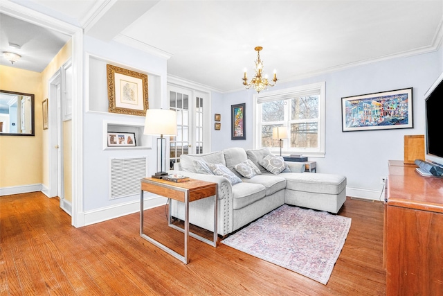 living area featuring visible vents, light wood-style flooring, an inviting chandelier, crown molding, and baseboards