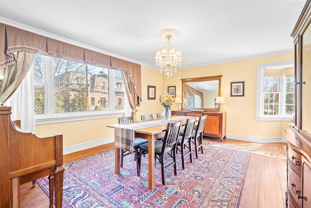 dining room featuring a notable chandelier, baseboards, light wood-type flooring, and ornamental molding