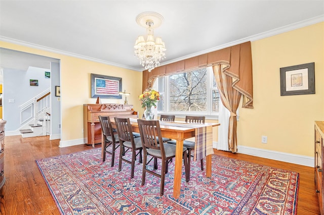 dining space featuring wood finished floors, an inviting chandelier, and ornamental molding