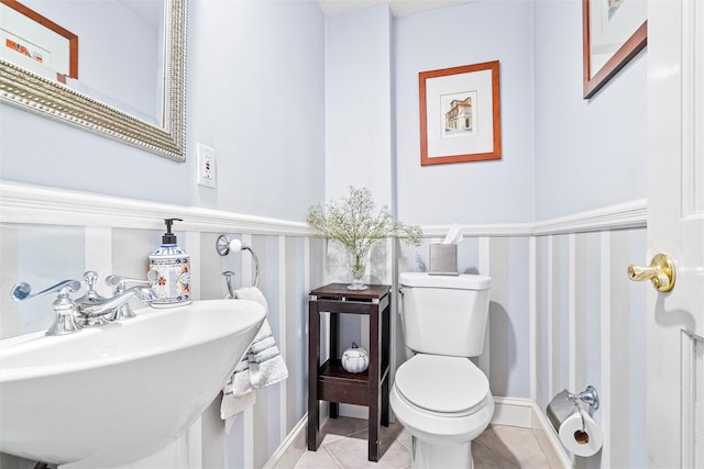 bathroom with a sink, toilet, and tile patterned flooring