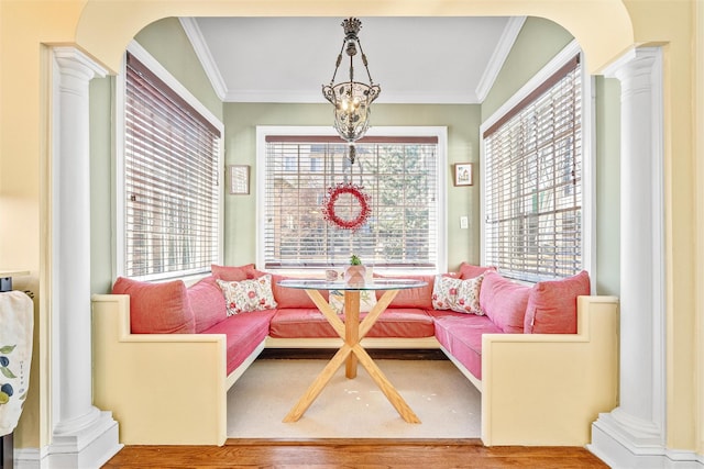 interior space featuring a wealth of natural light, ornamental molding, wood finished floors, and decorative columns