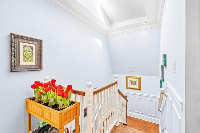 stairs with lofted ceiling, wood finished floors, and ornamental molding