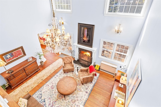 living room featuring a chandelier, a fireplace with flush hearth, visible vents, and wood finished floors