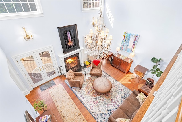 living room with baseboards, a notable chandelier, a warm lit fireplace, and light wood finished floors