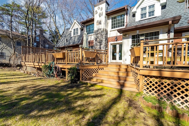 back of property with roof with shingles, a yard, a chimney, french doors, and a deck