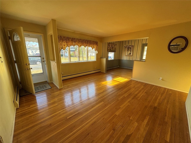 empty room with hardwood / wood-style floors and a baseboard heating unit