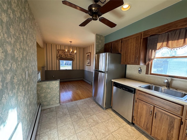 kitchen featuring ceiling fan with notable chandelier, a baseboard radiator, pendant lighting, stainless steel appliances, and sink