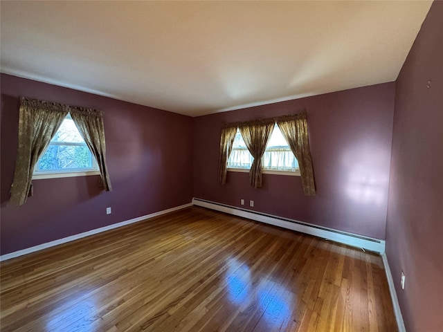 spare room with a baseboard heating unit and hardwood / wood-style flooring