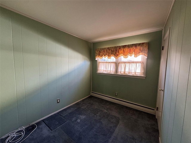 empty room with wood walls, dark carpet, and a baseboard radiator