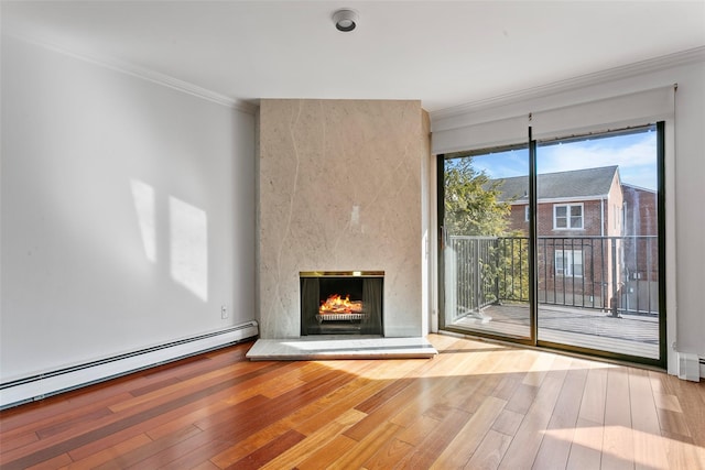 unfurnished living room with baseboard heating, ornamental molding, wood-type flooring, and a fireplace