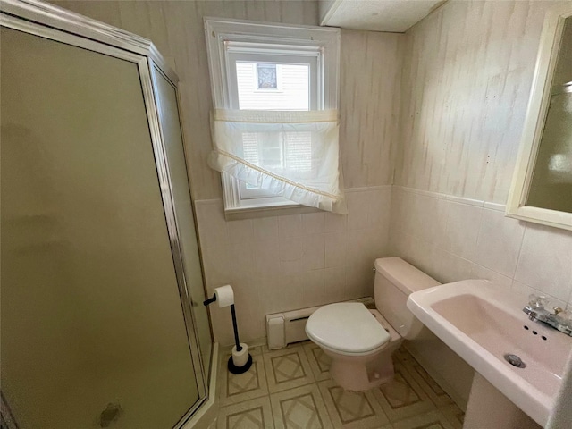 bathroom featuring walk in shower, toilet, sink, and tile walls