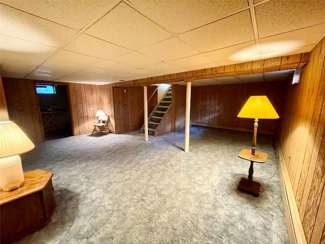 basement with carpet flooring, a paneled ceiling, and baseboard heating