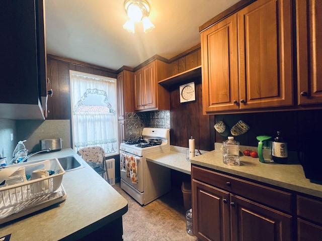 kitchen featuring white gas stove, decorative backsplash, and sink