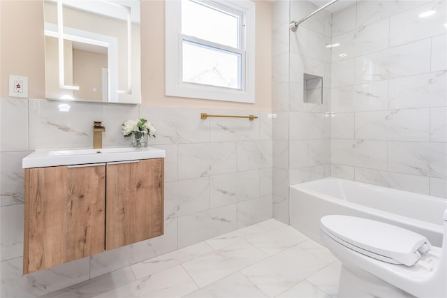 full bathroom featuring tiled shower / bath, tile walls, vanity, and toilet