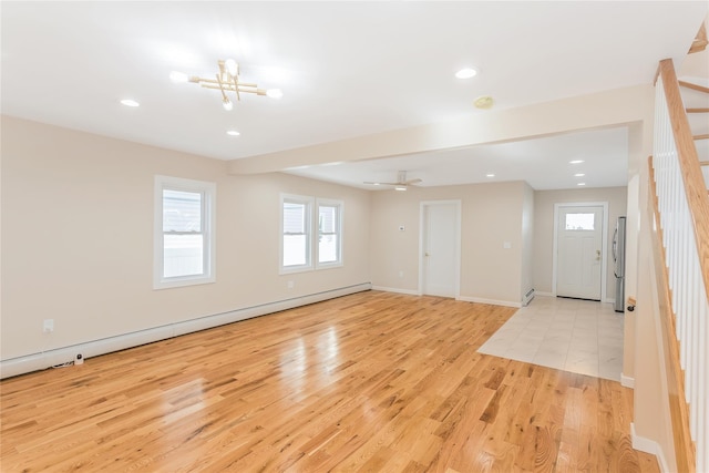 interior space with a baseboard heating unit, ceiling fan with notable chandelier, and light wood-type flooring