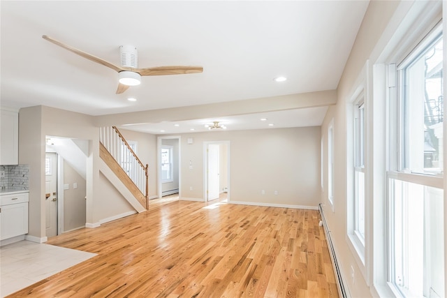 unfurnished living room with baseboard heating, ceiling fan, and light wood-type flooring