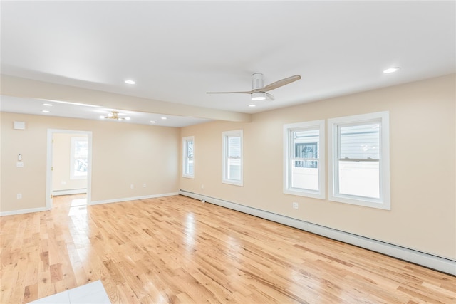 empty room featuring baseboard heating, ceiling fan, and light wood-type flooring