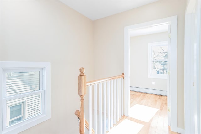 hall featuring a baseboard heating unit and light hardwood / wood-style flooring