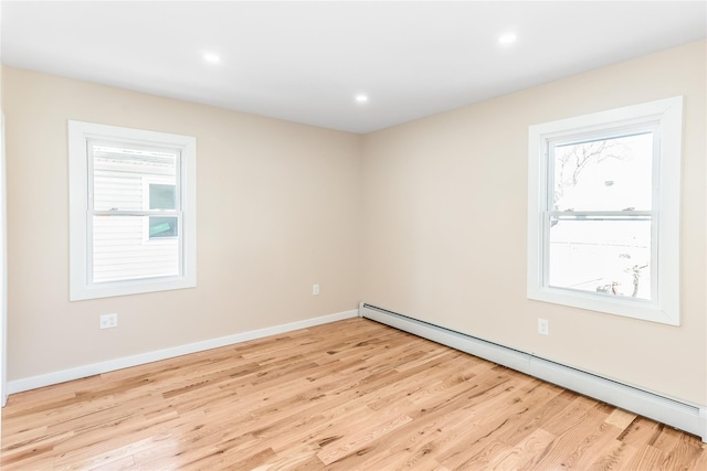 empty room with light wood-type flooring and a baseboard heating unit