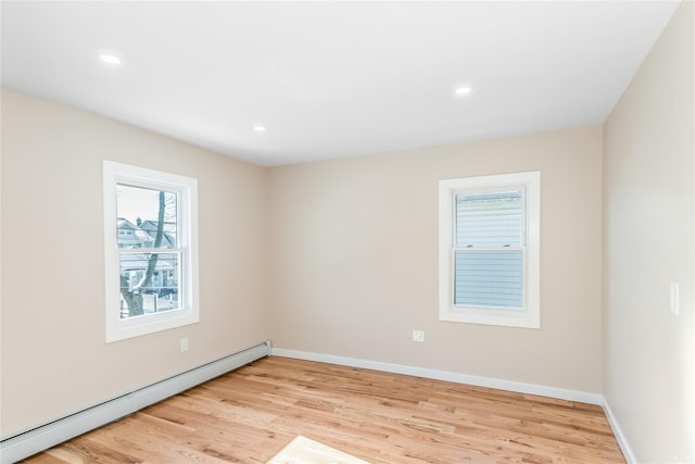 unfurnished room featuring baseboard heating and light hardwood / wood-style floors