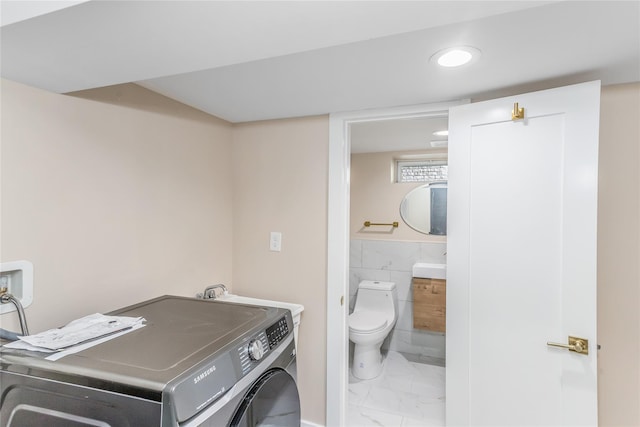 clothes washing area with washer / dryer, sink, and tile walls