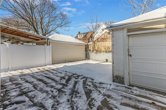 yard layered in snow featuring a garage and an outdoor structure