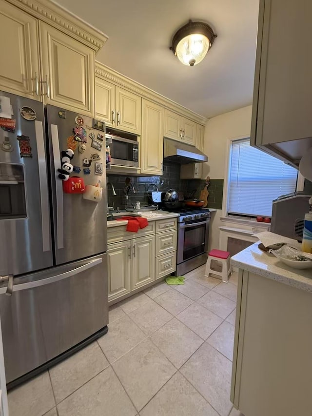 kitchen featuring light tile patterned flooring, appliances with stainless steel finishes, cream cabinetry, and tasteful backsplash