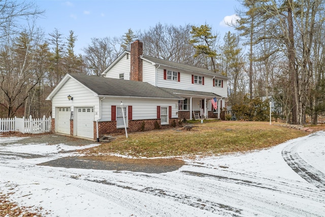 view of property featuring a garage, a lawn, and covered porch