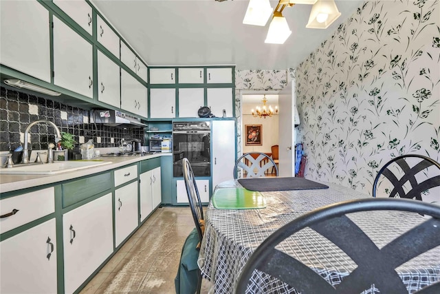 kitchen featuring an inviting chandelier, backsplash, white cabinets, and sink