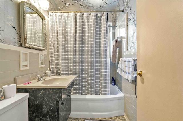 full bathroom featuring toilet, tile walls, sink, and shower / bath combo