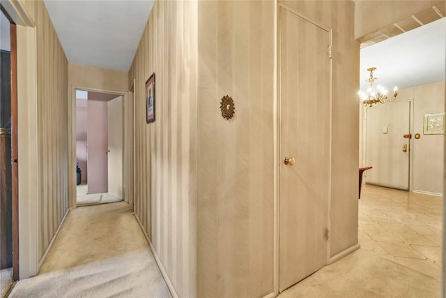 hall featuring light colored carpet and a notable chandelier