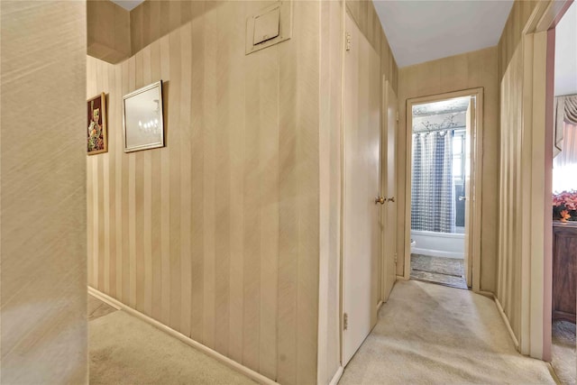 corridor with light carpet and wood walls