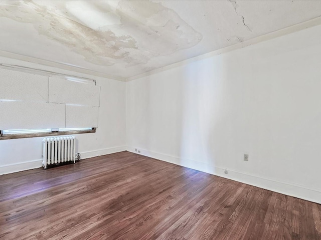 spare room featuring hardwood / wood-style floors and radiator heating unit