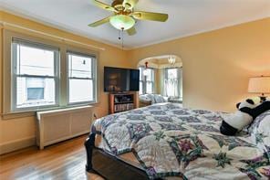 bedroom with ceiling fan, crown molding, and hardwood / wood-style flooring