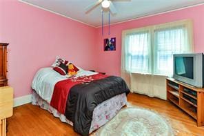 bedroom with ceiling fan, crown molding, and light hardwood / wood-style flooring