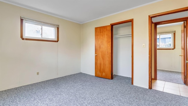 unfurnished bedroom featuring light carpet, a closet, crown molding, and multiple windows