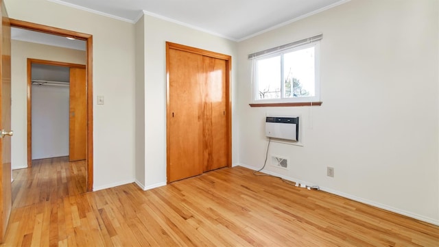 unfurnished bedroom with a closet, heating unit, crown molding, and light wood-type flooring