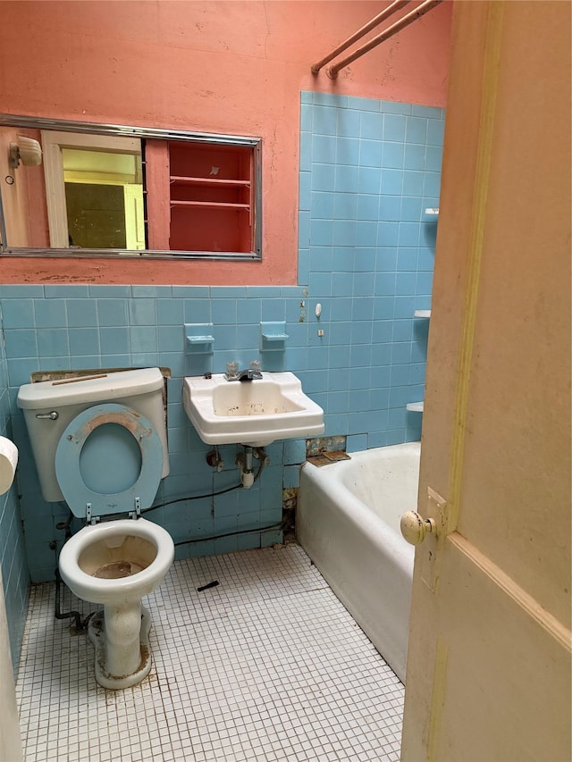 bathroom with toilet, tile patterned flooring, tile walls, and sink