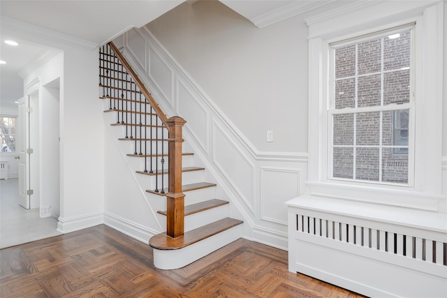 stairway featuring crown molding, parquet flooring, and radiator heating unit